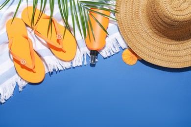 Photo of Beach accessories and palm leaf on blue background, flat lay. Space for text