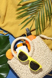Photo of Beach accessories and palm leaves on blue background, flat lay