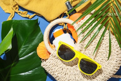 Photo of Beach accessories and palm leaves on blue background, flat lay