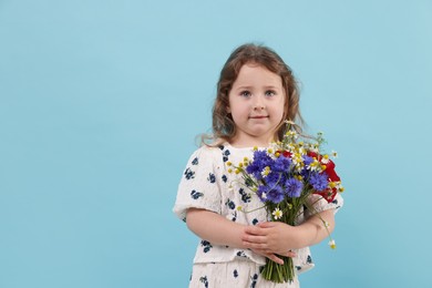 Photo of Cute little girl with bouquet of beautiful flowers on light blue background, space for text