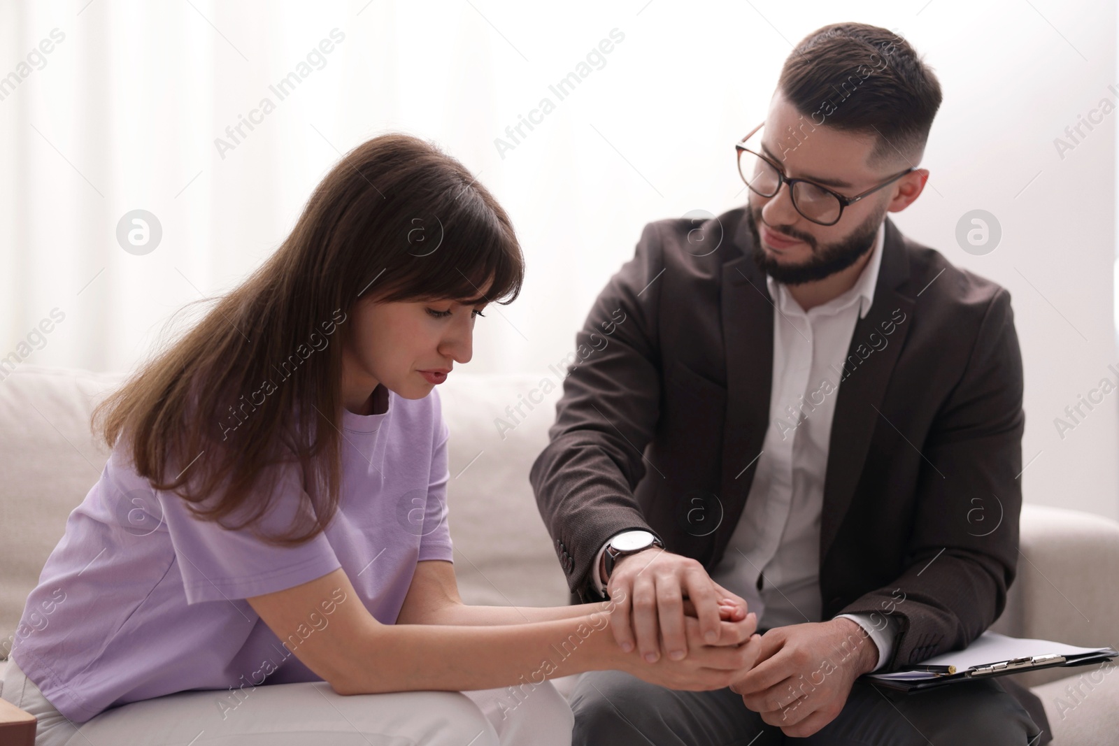 Psychologist supporting patient during therapy session on sofa in office Photo of Psychologist supporting patient during therapy session on sofa in office
