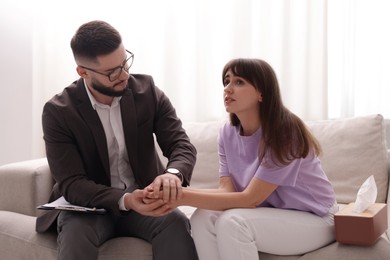 Photo of Psychologist supporting patient during therapy session on sofa in office
