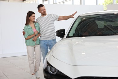 Photo of Happy family near new car in salon