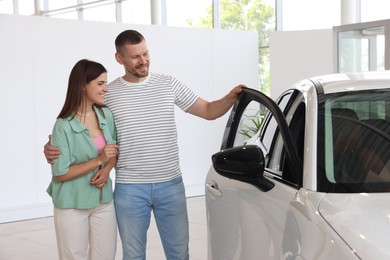 Photo of Happy family near new car in salon