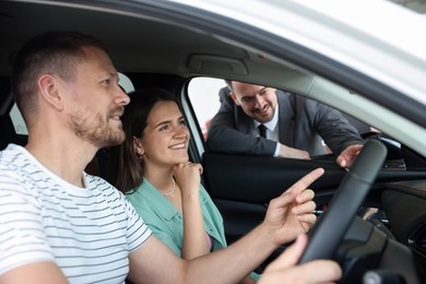 Photo of Salesman showing new car to happy family