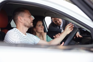 Photo of Salesman showing new car to happy family, selective focus