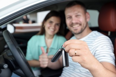 Photo of Happy family with keys inside new car, selective focus