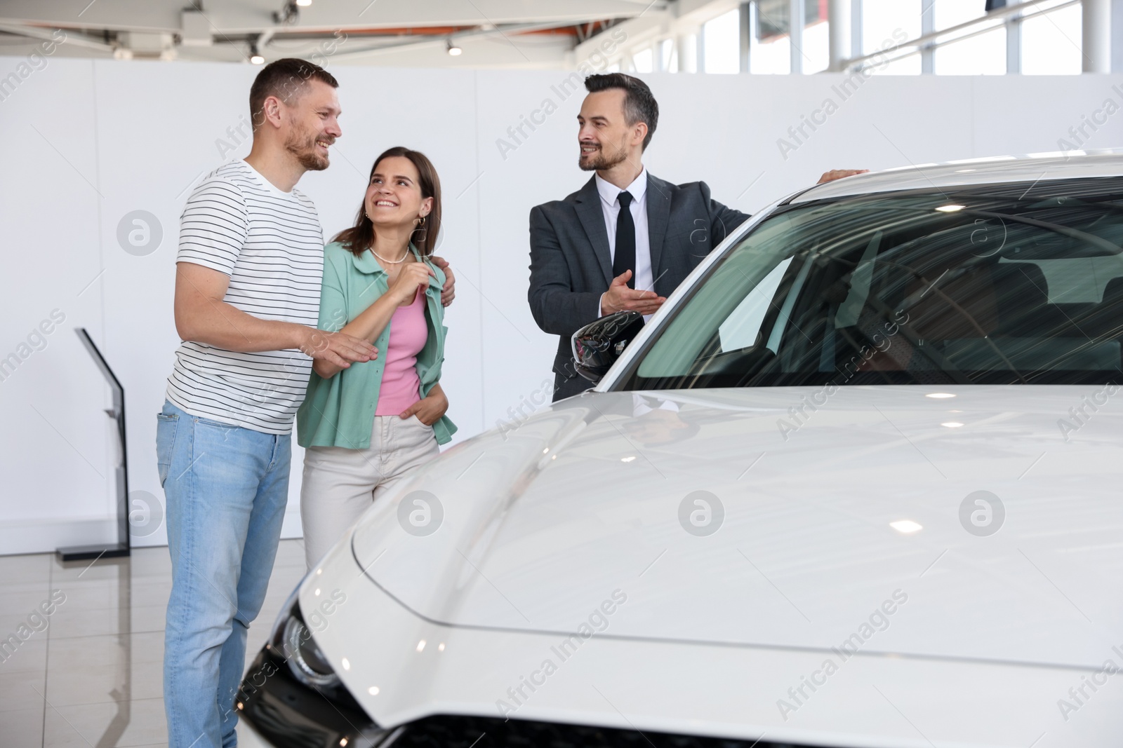 Photo of Salesman showing new car to happy family in salon