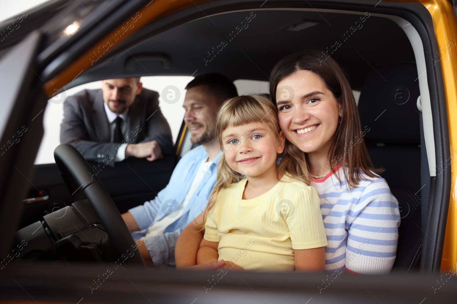 Photo of Salesman showing new car to happy family, selective focus