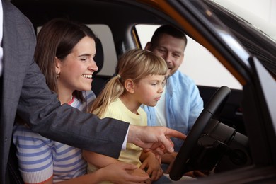 Photo of Salesman showing new car to happy family, closeup