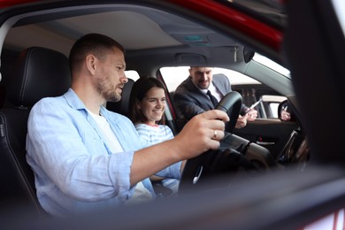 Photo of Salesman showing new car to happy family, selective focus