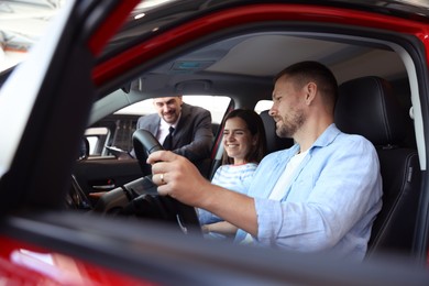 Photo of Salesman showing new car to happy family, selective focus