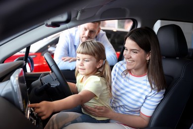 Photo of Happy family sitting inside new car. Luxury vehicle