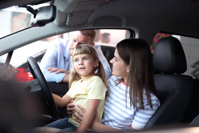 Photo of Happy family sitting inside new car. Luxury vehicle
