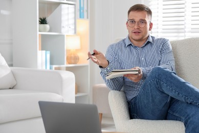 Photo of Psychologist in glasses talking during session near laptop in office