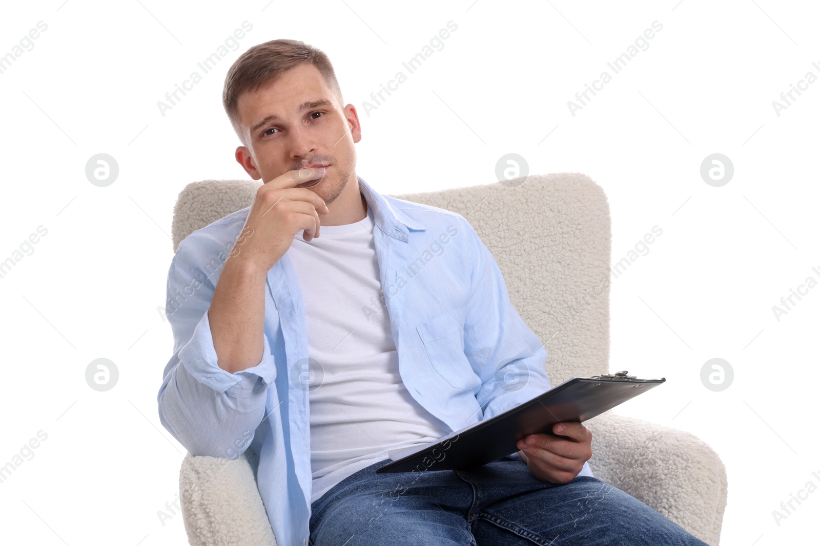Photo of Thoughtful psychologist with clipboard sitting on armchair against white background