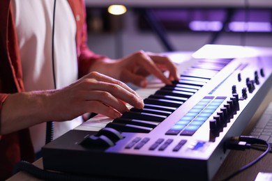 Photo of Man working with MIDI keyboard at table indoors, closeup