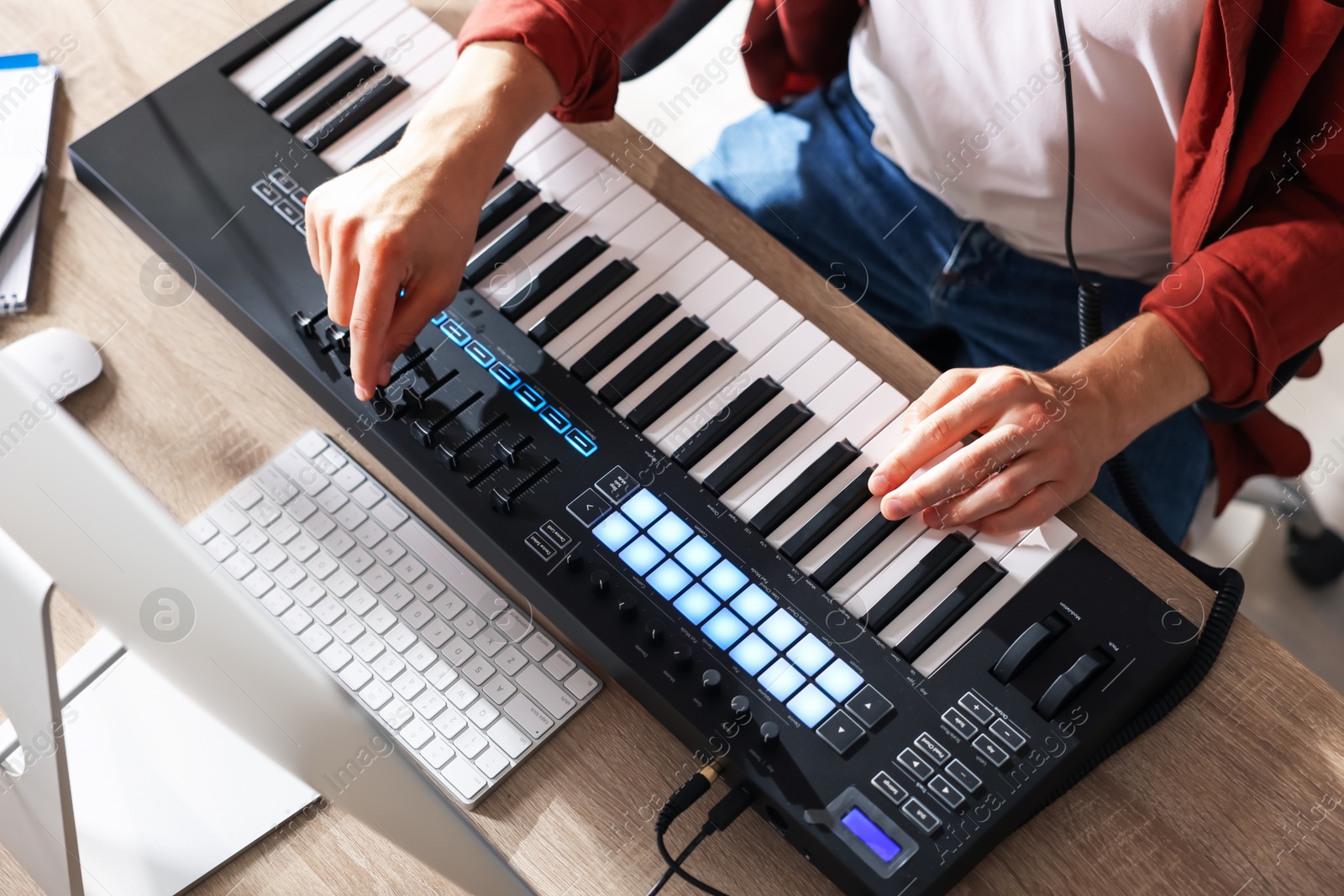 Photo of Man working with MIDI keyboard at wooden table indoors, above view