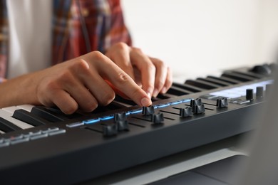 Photo of Man working with MIDI keyboard at table indoors, closeup