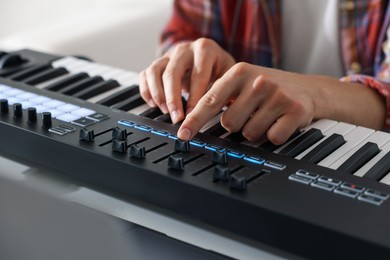 Photo of Man working with MIDI keyboard at table indoors, closeup