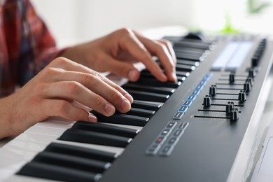 Photo of Man working with MIDI keyboard at table indoors, closeup