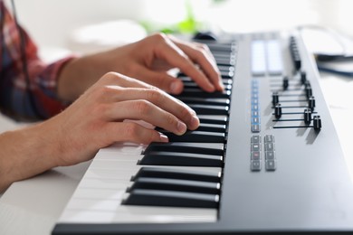Photo of Man working with MIDI keyboard at table indoors, closeup