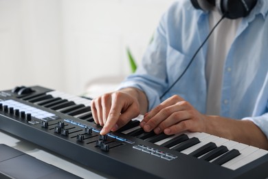 Photo of Man working with MIDI keyboard at table indoors, closeup