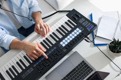 Photo of Man working with MIDI keyboard at white table indoors, above view