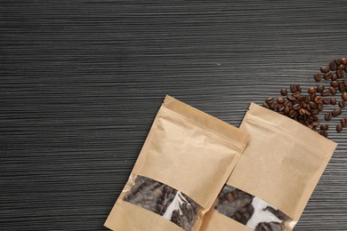 Photo of Zipper stand-up pouches and coffee beans on black textured table, flat lay. Mockup for design