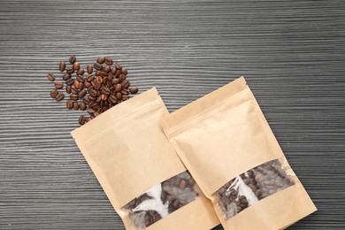 Photo of Zipper stand-up pouches and coffee beans on black textured table, flat lay. Mockup for design