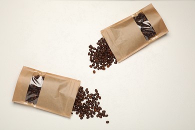 Photo of Zipper stand-up pouches and coffee beans on white table, flat lay. Mockup for design