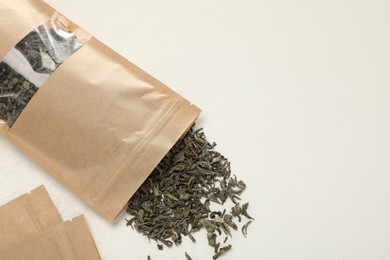 Photo of Zipper stand-up pouches and dry leaves on white table, flat lay. Mockup for design