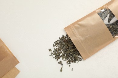 Photo of Zipper stand-up pouches and dry leaves on white table, flat lay. Mockup for design