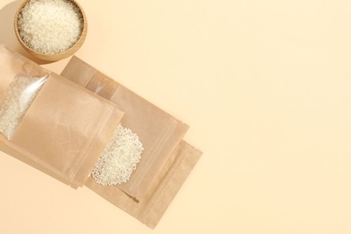 Photo of Zipper stand-up pouches with white rice on beige background, flat lay. Mockup for design