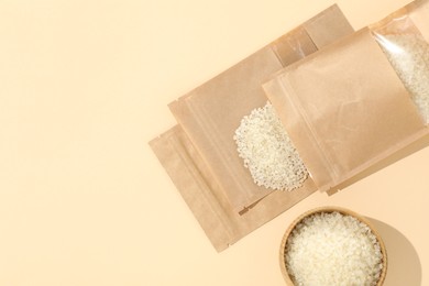 Photo of Zipper stand-up pouches with white rice on beige background, flat lay. Mockup for design