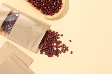 Photo of Zipper stand-up pouches and dry kidney beans on beige background, flat lay. Mockup for design