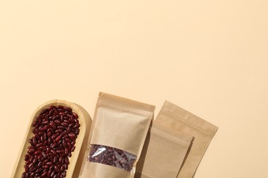 Photo of Zipper stand-up pouches and dry kidney beans on beige background, flat lay. Mockup for design