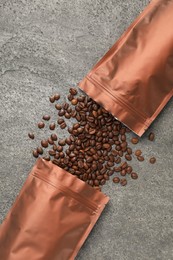 Photo of Zipper stand-up pouches and coffee beans on grey table, flat lay. Mockup for design