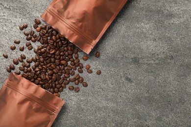 Photo of Zipper stand-up pouches and coffee beans on grey table, flat lay. Space for text