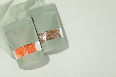 Photo of Zipper stand-up pouches with different products on light background, flat lay. Mockup for design