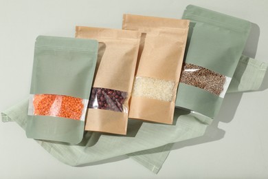 Photo of Zipper stand-up pouches with different products on light background, flat lay. Mockup for design