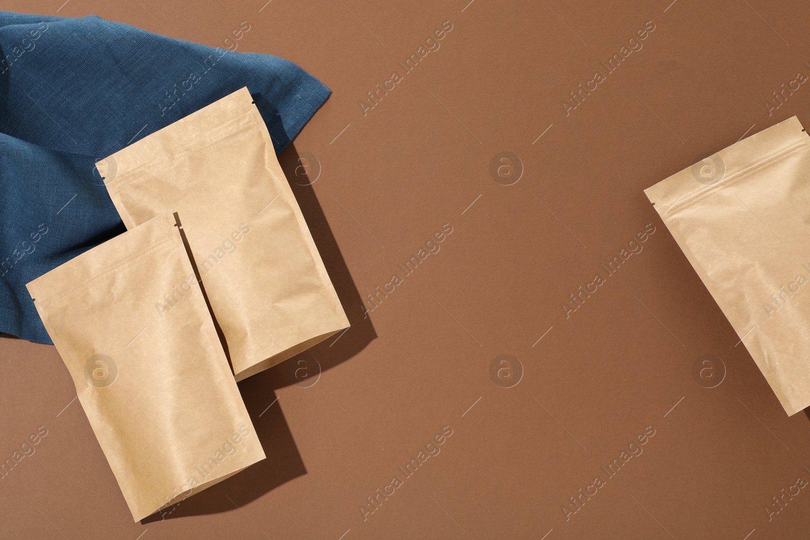 Zipper stand-up pouches on brown background, flat lay. Mockup for design Photo of Zipper stand-up pouches on brown background, flat lay. Mockup for design