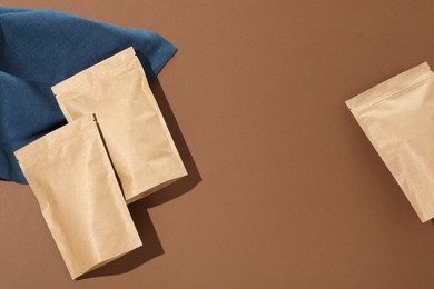 Photo of Zipper stand-up pouches on brown background, flat lay. Mockup for design