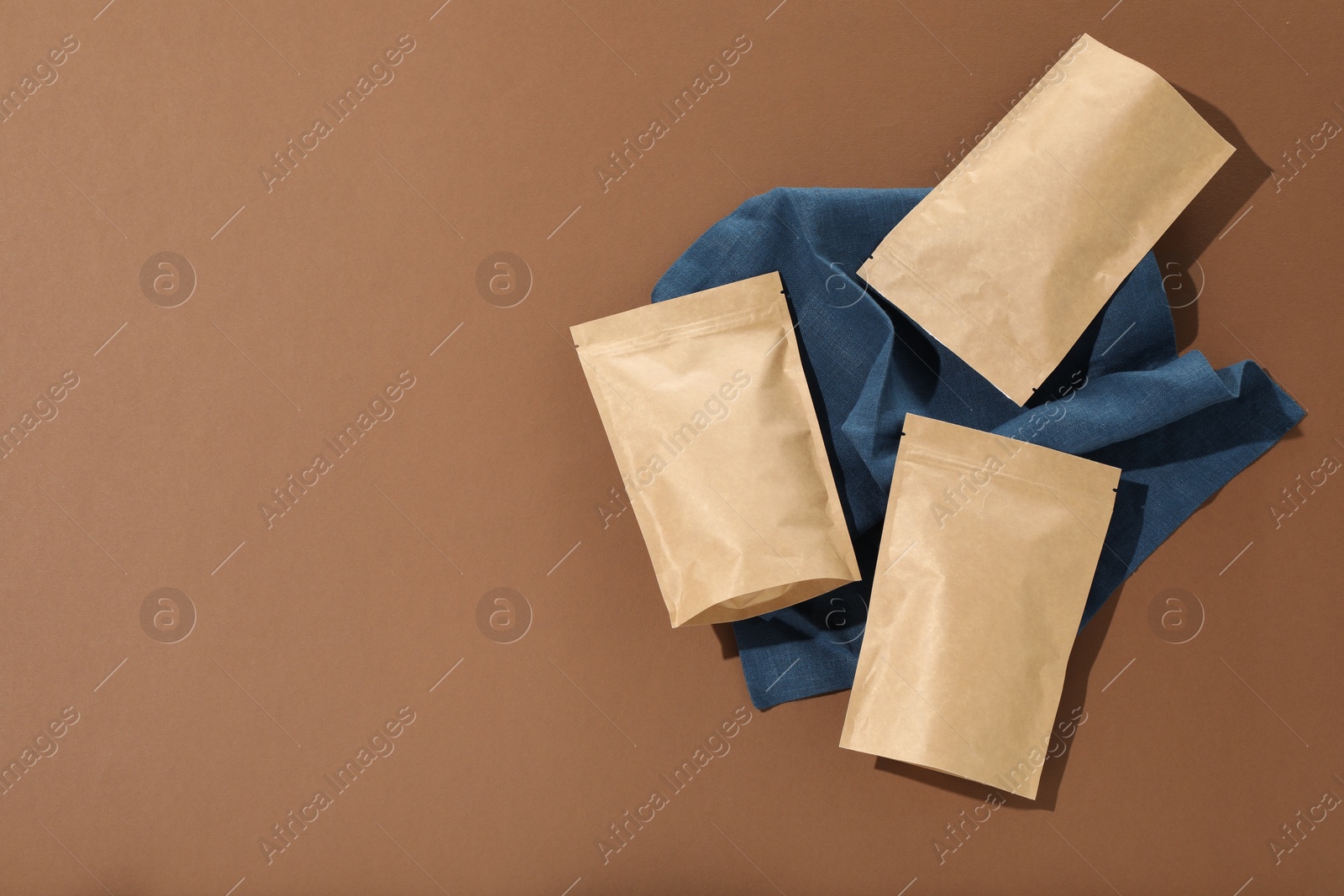Photo of Zipper stand-up pouches on brown background, flat lay. Mockup for design
