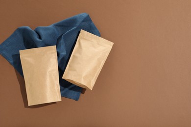 Photo of Zipper stand-up pouches on brown background, flat lay. Mockup for design