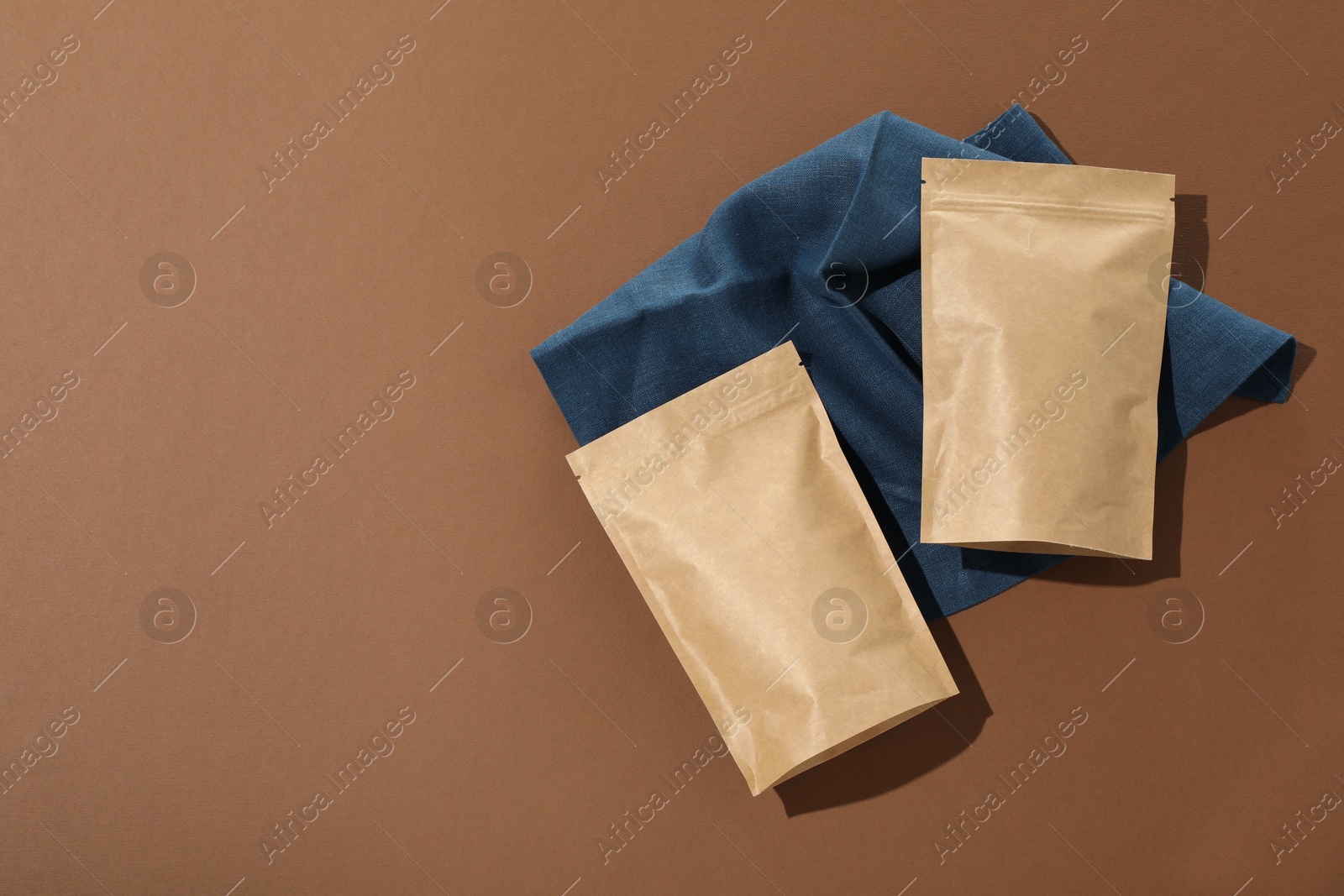 Zipper stand-up pouches on brown background, flat lay. Mockup for design Photo of Zipper stand-up pouches on brown background, flat lay. Mockup for design