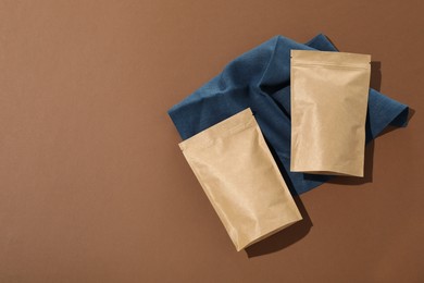 Photo of Zipper stand-up pouches on brown background, flat lay. Mockup for design
