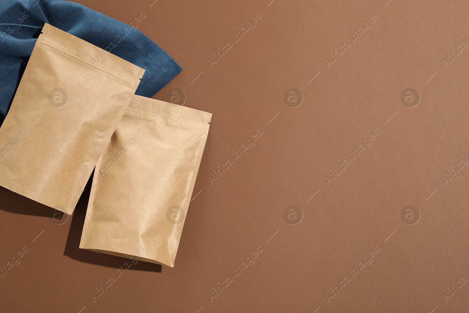 Zipper stand-up pouches on brown background, flat lay. Mockup for design Photo of Zipper stand-up pouches on brown background, flat lay. Mockup for design