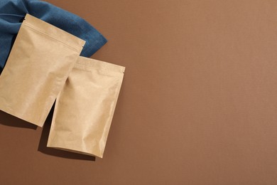 Photo of Zipper stand-up pouches on brown background, flat lay. Mockup for design