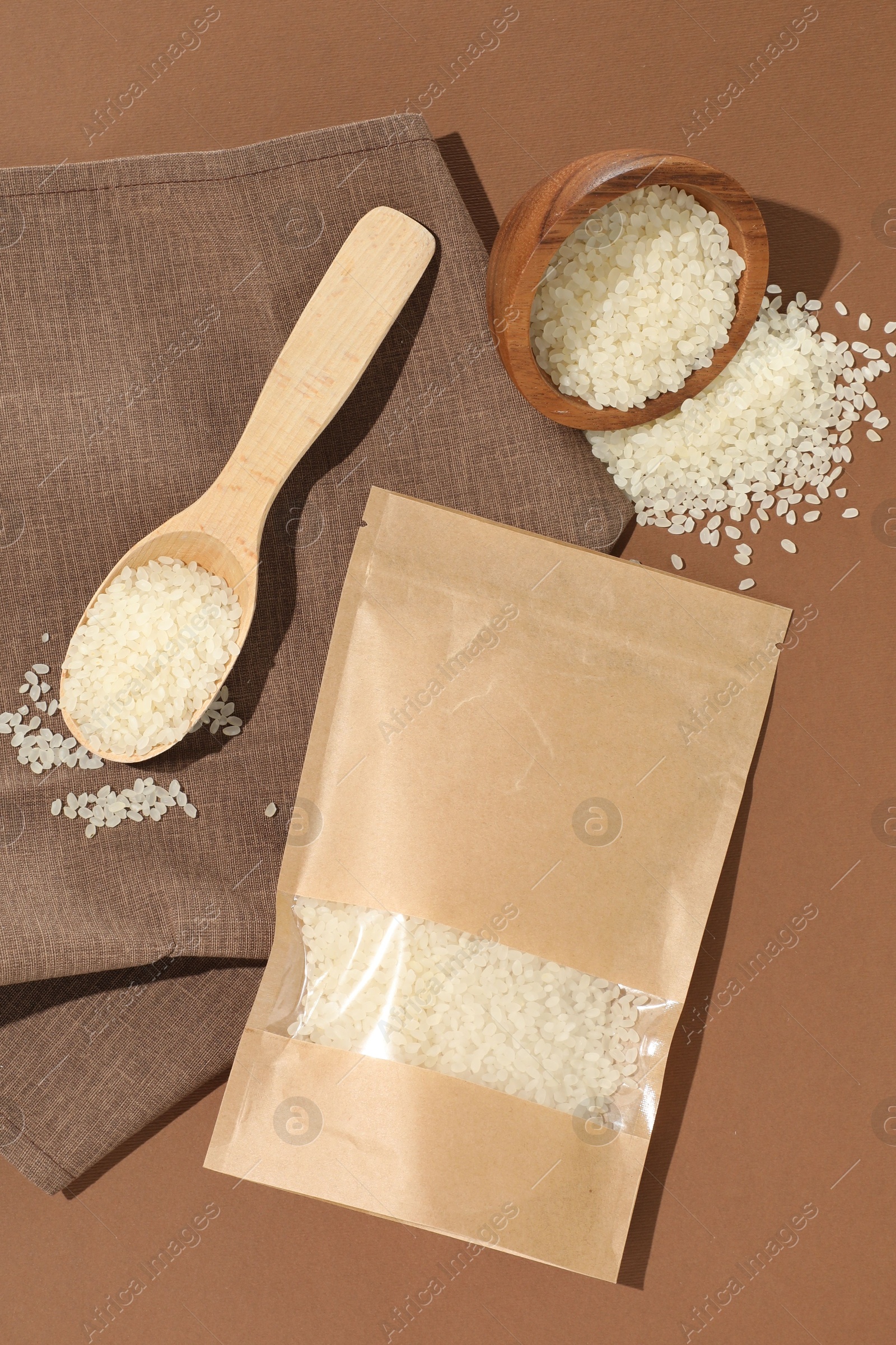 Zipper stand-up pouch and white rice on brown background, flat lay. Mockup for design Photo of Zipper stand-up pouch and white rice on brown background, flat lay. Mockup for design